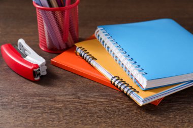 Ev ödevi. Defterler ve ahşap masadaki farklı kırtasiye malzemeleri.