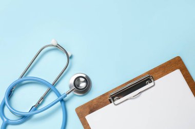 Açık mavi arka planda steteskop ve pano, üst manzara. Metin için boşluk