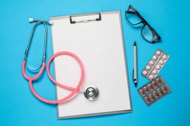 Açık mavi zemin üzerinde stetoskop ve pano ile düz konum
