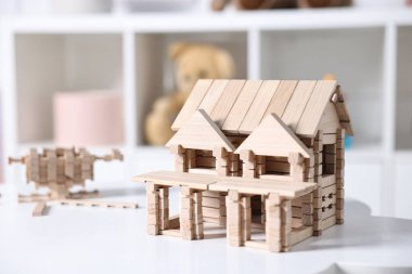 Beyaz masadaki tahta bloklardan yapılmış ev figürü. Kapalı, yakın plan.
