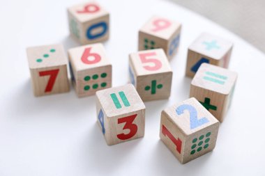 Beyaz masa üzerinde sayılar ve semboller olan tahta küpleri, yakın plan.