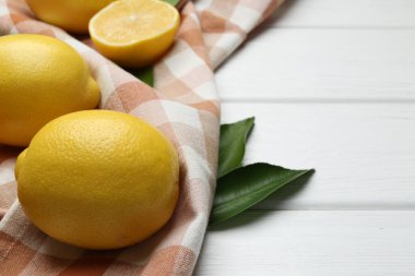 Taze limon meyveleri ve beyaz ahşap masada yeşil yapraklar, yakın plan. Metin için boşluk