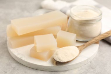 Jelatin tozu ve jöle parçaları gri masada, yakın plan.