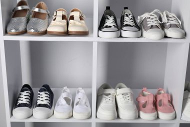 Raf ünitesinde farklı stil çocuk ayakkabıları var. Kapalı, yakın çekim.