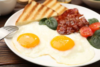 Yağda yumurta ve pastırma ile nefis bir kahvaltı, ahşap masada servis edilir, yakın plan.