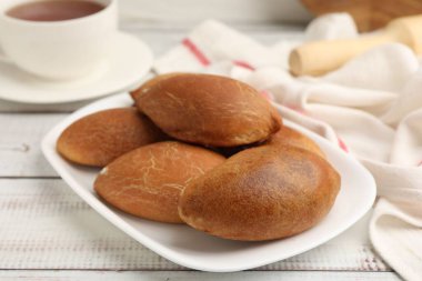 Lezzetli fırında köfteler, beyaz ahşap masada çay ile servis edilir, yakın plan.