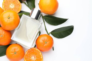 Beyaz arka planda bir şişe parfüm ve mandalina.