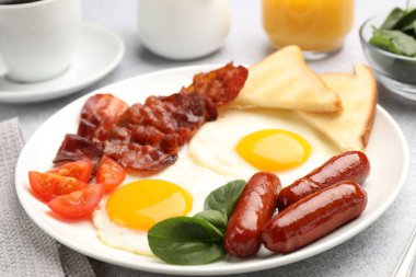 Açık gri masada servis edilen yağda yumurta, sosis ve pastırma ile nefis bir kahvaltı.