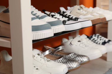 İçerideki raflarda farklı stil çocuk ayakkabıları, yakın plan.