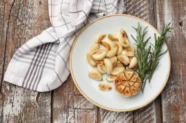 Ahşap masada biberiyeli ızgara sarımsak karanfili.