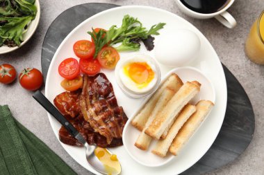 Gri masada servis edilen kaynamış yumurta ve pastırmalı lezzetli bir kahvaltı.