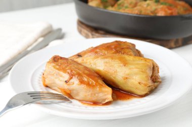 Beyaz masada servis edilen lezzetli lahana dürümleri, yakın plan.