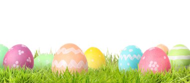 Beyaz arka plana karşı yeşil çimlerde paskalya yumurtaları