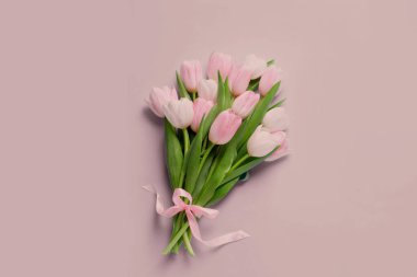 Pembe arka planda kurdeleli bir buket güzel lale.