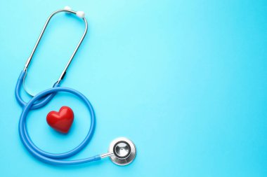Açık mavi arka planda steteskop ve kalp modeli. Metin için boşluk
