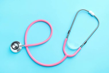 Açık mavi arkaplanda pembe steteskop, üst görünüm