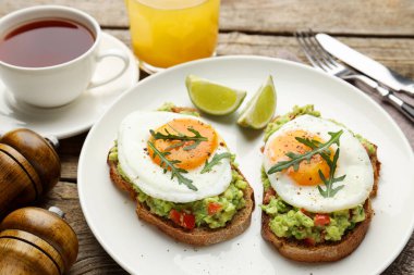 Avokado tostlu sağlıklı kahvaltı ahşap masada servis edilir, yakın plan.