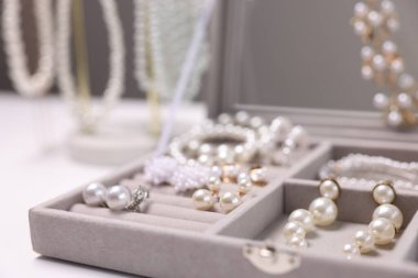 Beyaz masadaki kutuda farklı tarz mücevherler, yakın plan.