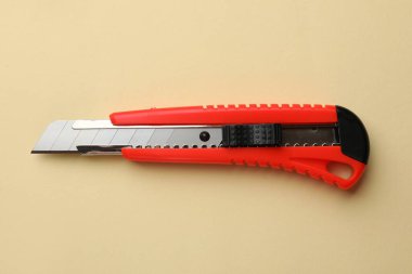 Bej arka planda keskin bir kağıt bıçak, üst manzara.