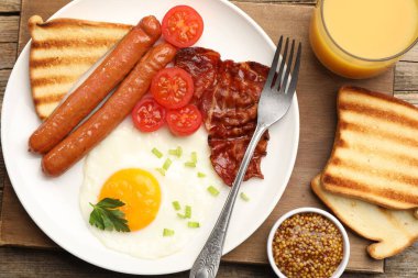 Tahta masada servis edilen kızarmış yumurta, sosis ve domuz pastırması ile nefis bir kahvaltı.