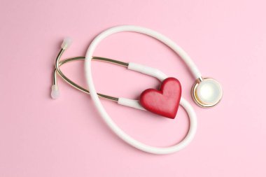 Kan basıncını ölçüyorum. Pembe arka planda steteskop ve kırmızı kalp figürü.
