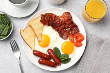 Yağda yumurta, sosis ve pastırma ile nefis bir kahvaltı açık gri masada servis edilir.