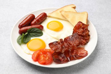 Açık gri masada servis edilen yağda yumurta, sosis ve pastırma ile nefis bir kahvaltı.