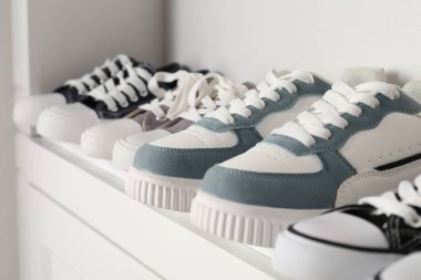 Beyaz raflarda farklı tarz çocuk ayakkabıları, yakın plan.