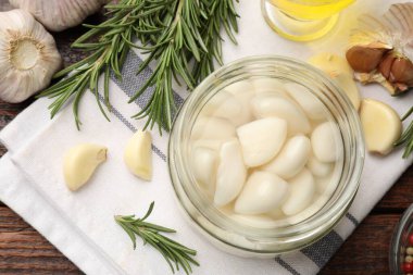 Cam kavanozda sarımsak turşusu ve ahşap masada baharatlar.