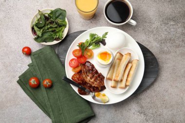 Gri masada servis edilen kaynamış yumurta ve pastırmalı lezzetli bir kahvaltı.