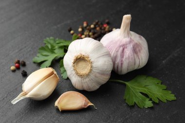 Taze sarımsak, biber ve maydanoz siyah masada, yakın plan.