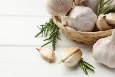 Beyaz ahşap masada taze sarımsak ve biberiye, yakın plan. Metin için boşluk