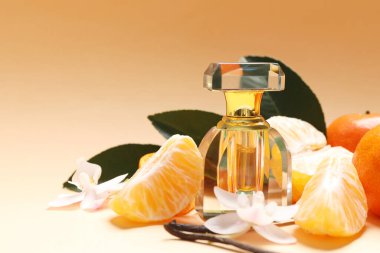 Bottle of aromatic perfume, fresh tangerines, green leaves, vanilla pods and orchid flowers on gradient beige background, closeup. Space for text
