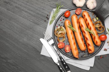 Izgara sosis, domates ve baharatlar siyah masada, düz yerde. Metin için boşluk