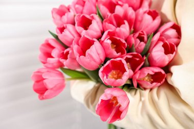 Kapalı alanda pembe lale çiçekli bir kadın, yakın plan.