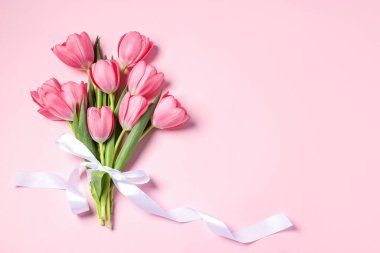 Pembe arka planda bir buket lale, üst manzara. Metin için boşluk