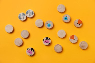 Sarı zemin üzerinde çocuk oyunu hayvanları olan ahşap parçalar, düz yatıyordu