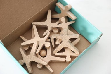 Denge oyunu. Tahta akrobatları beyaz masanın üstünde kutuda istiflemek, yakın plan.