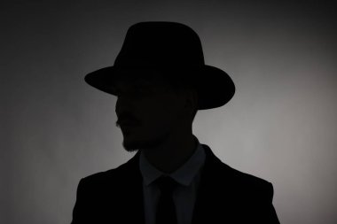 Silhouette of man in hat on dark background