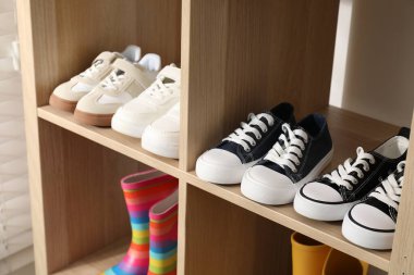 Raf ünitesinde farklı stil çocuk ayakkabıları var. Kapalı, yakın çekim.