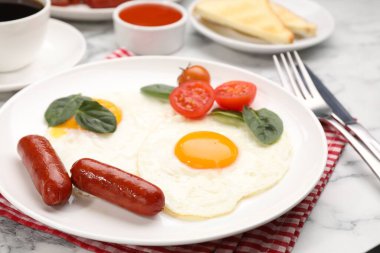 Beyaz mermer masada servis edilen omlet ve sosislerle nefis bir kahvaltı.