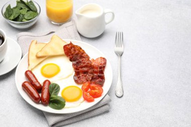 Açık gri masada servis edilen kızarmış yumurta, sosis ve pastırma ile nefis bir kahvaltı. Metin için boşluk