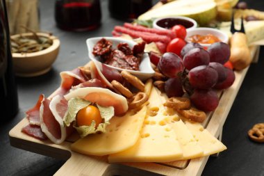 Siyah masada farklı atıştırmalıklar ve şaraplar olan şarküteri tahtası, yakın plan.