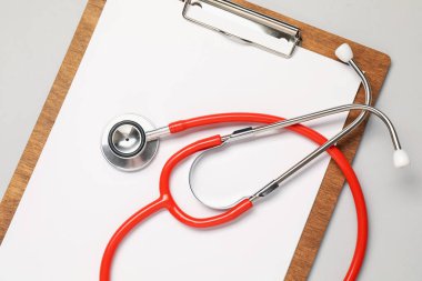 Açık gri arkaplanda stetoskop ve pano, üst görünüm