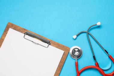Açık mavi arka planda steteskop ve pano, üst manzara. Metin için boşluk