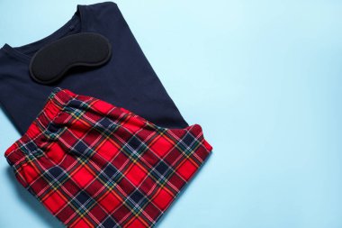 Açık mavi arka planda şık pijamalar ve uyku maskesi, üst manzara. Metin için boşluk