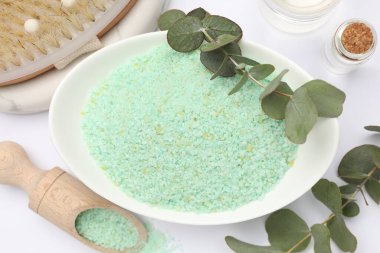 Kasede yeşil deniz tuzu, kepçe, fırça, temel yağlar ve beyaz zemin üzerinde okaliptüs dalları, düz uzanmış