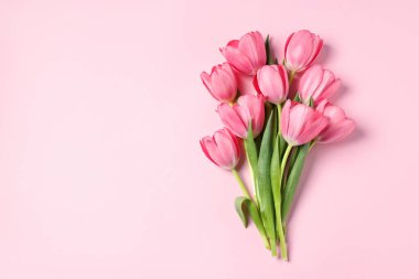 Pembe arka planda bir buket lale, üst manzara. Metin için boşluk