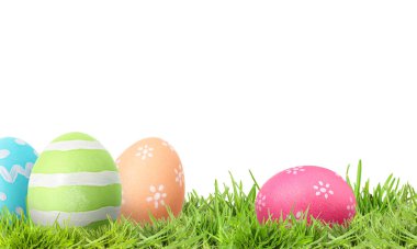 Beyaz arka plana karşı yeşil çimlerde paskalya yumurtaları