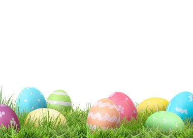 Beyaz arka plana karşı yeşil çimlerde paskalya yumurtaları